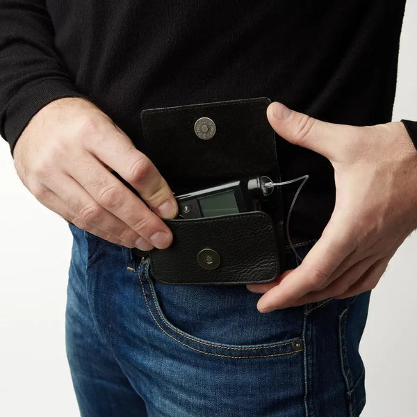 Leather insulin pump holder worn on pants with secure flap open, showcasing stylish design and easy access.