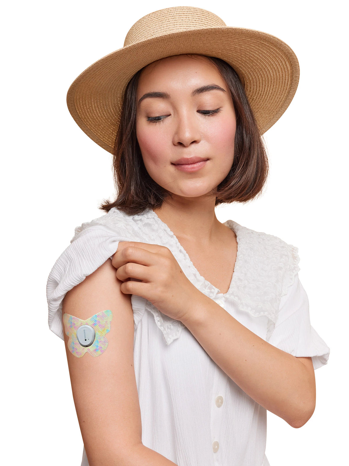 Patch adhésif Dexcom G7, forme papillon, porté sur le bras d'une femme
