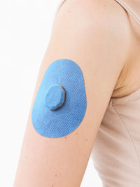 Patch adhésif Dexcom G7, forme goutte, sur le bras, gros plan